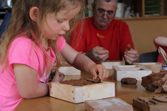 Une petite fille en train de réaliser son carreau en argile