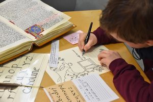 Un enfant, penché sur sa feuille, en train d'écrire à la plume